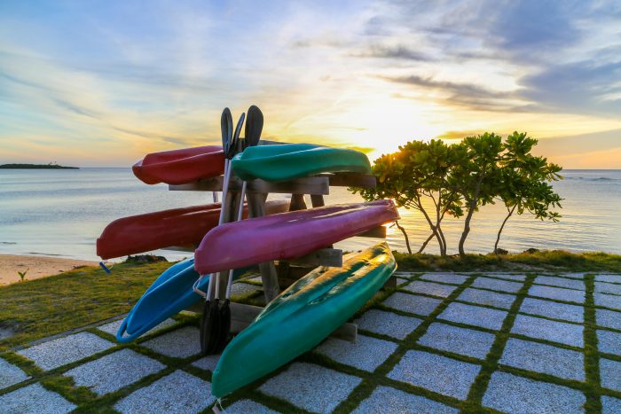 Vibrant kayaks stacked on a seaside rack at sunset in the Philippines, perfect for a serene adventure.