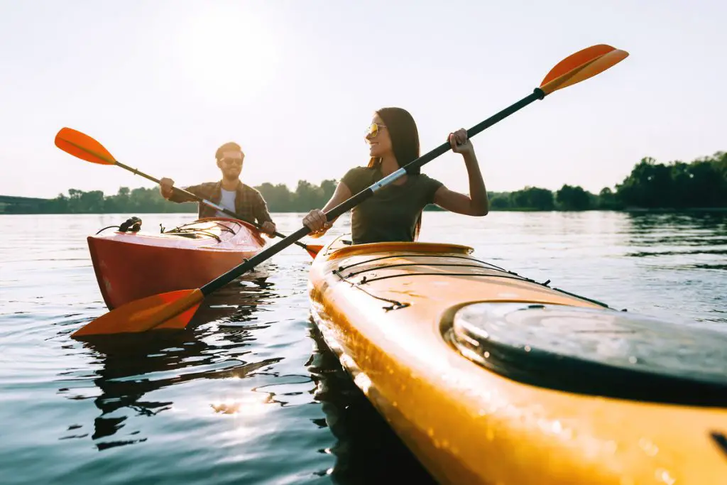 Nice day on the lake. Beautiful young couple kayaking on lake together and smiling