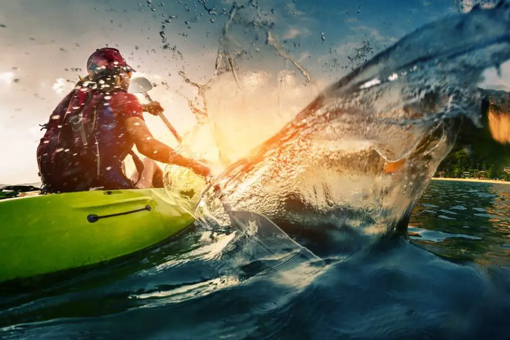 Young lady paddling hard the kayak with lots of splashes