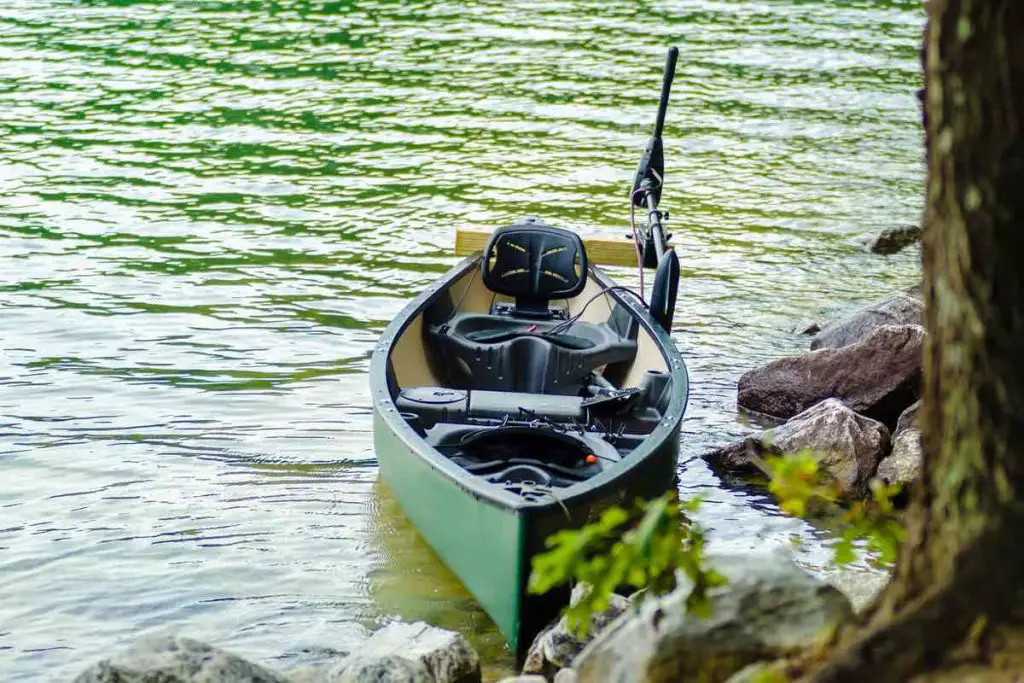 kayak with electric motor dosked to rocks on the lake