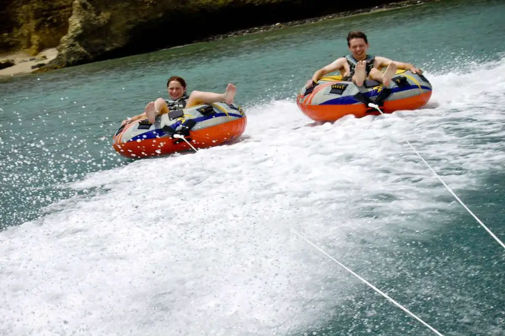 Two teenagers being pulled at high speed in inflatable tubes