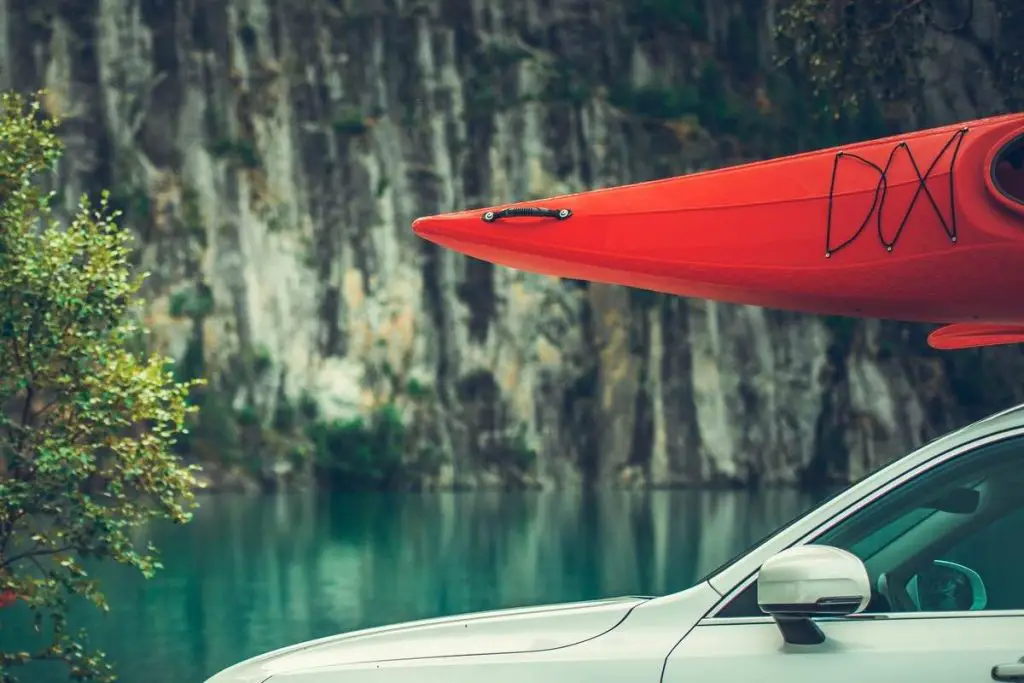 Summer Kayaking Tour. Red Kayak on the Car Roof. Water Sport Theme.