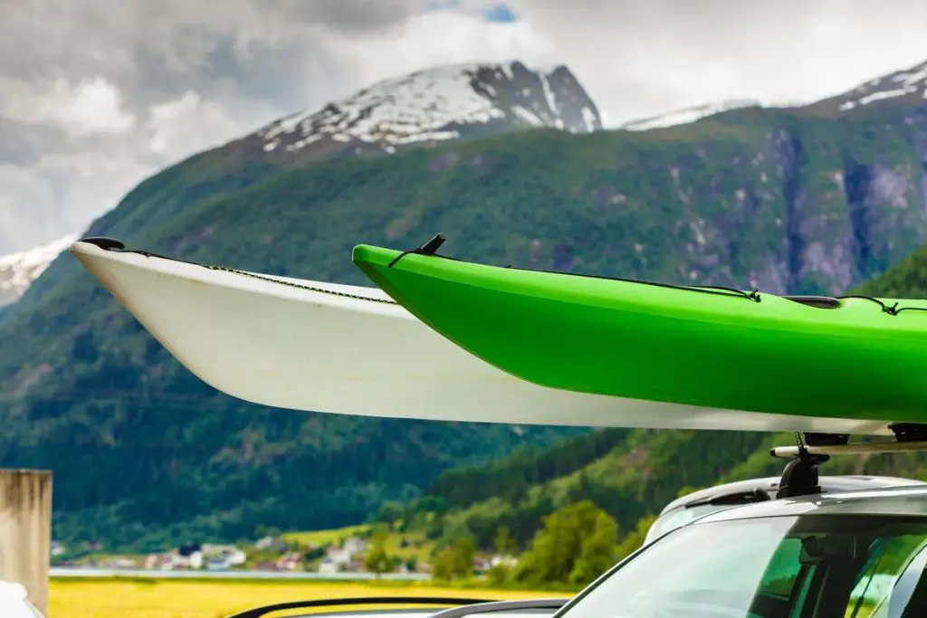 Active lifestyle sport concept. Car with two canoes white and green on top roof, mountains landscape in the background