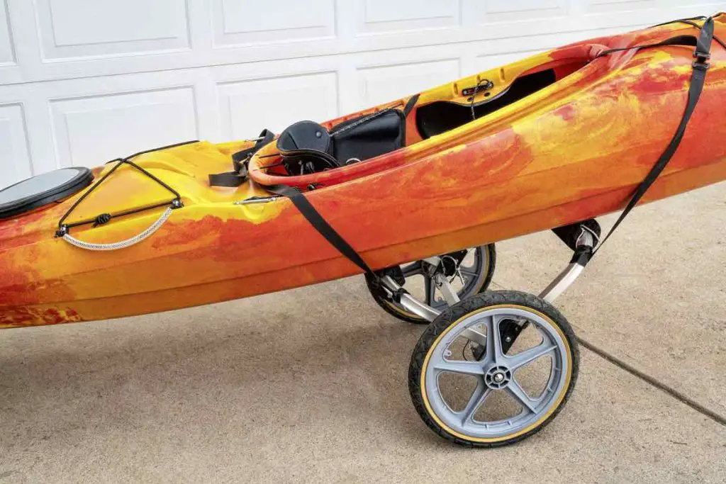 colorful river kayak on a folding cart in a driveway - river running shuttle concept