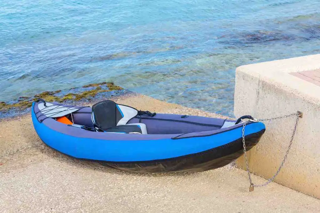 Chained blue canoe parked at shore with sea water