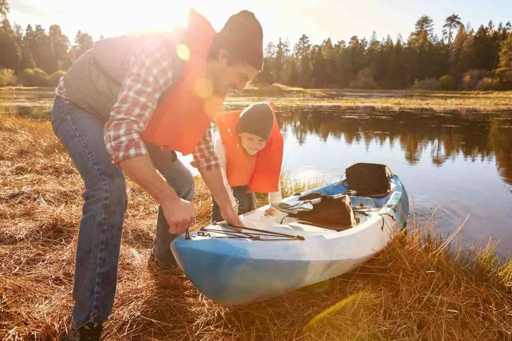 Father and son preparing kayak for launch from lakeside