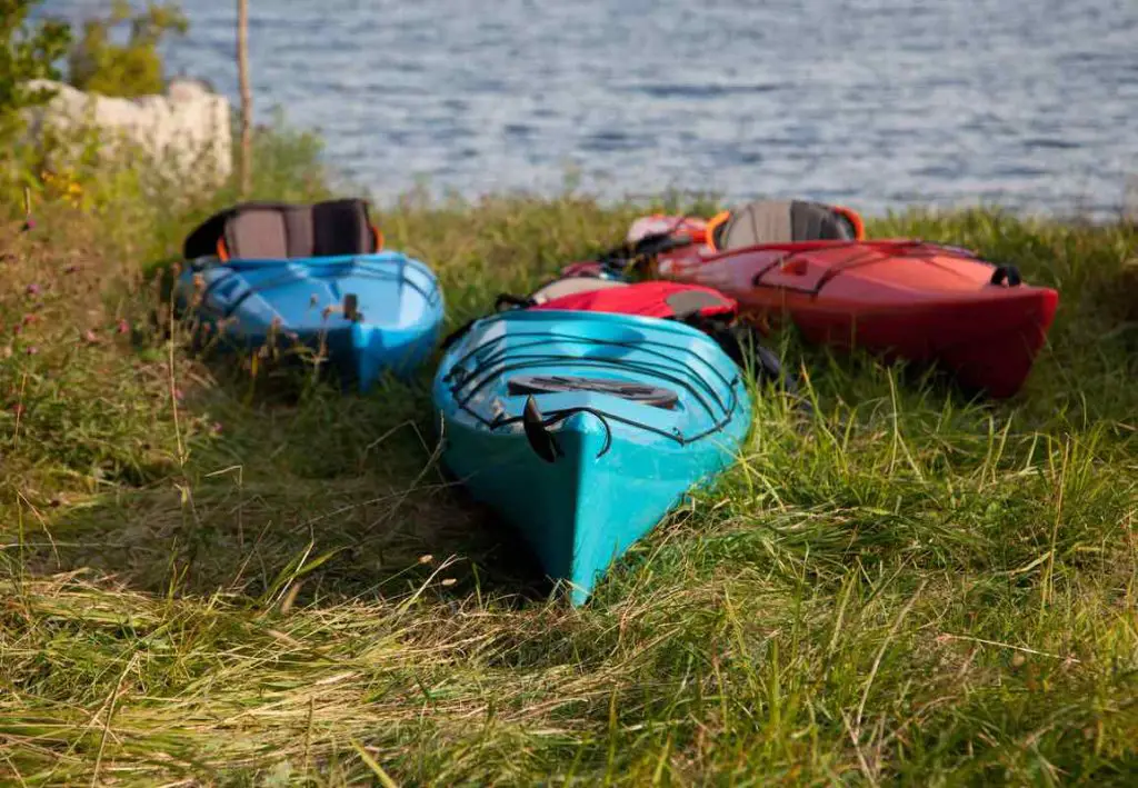 three colorful kayaks ready for a paddle or adventure by the shoreline