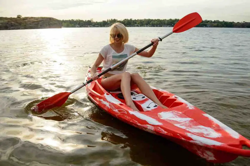 Young Happy Woman Paddling Kayak on the Beautiful River or Lake at Sunset