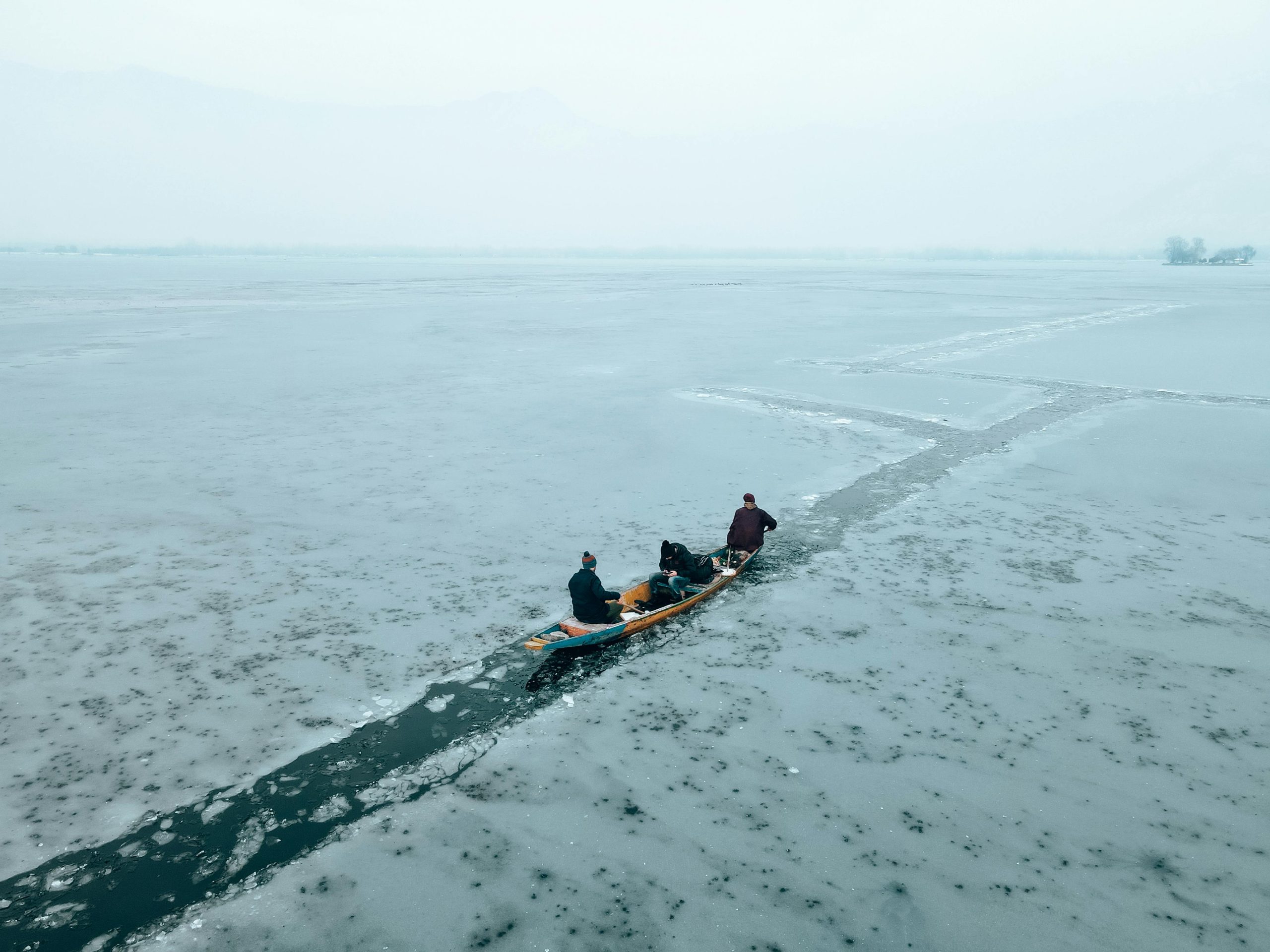 A group of people kayaking through icy waters on a frozen lake during winter.