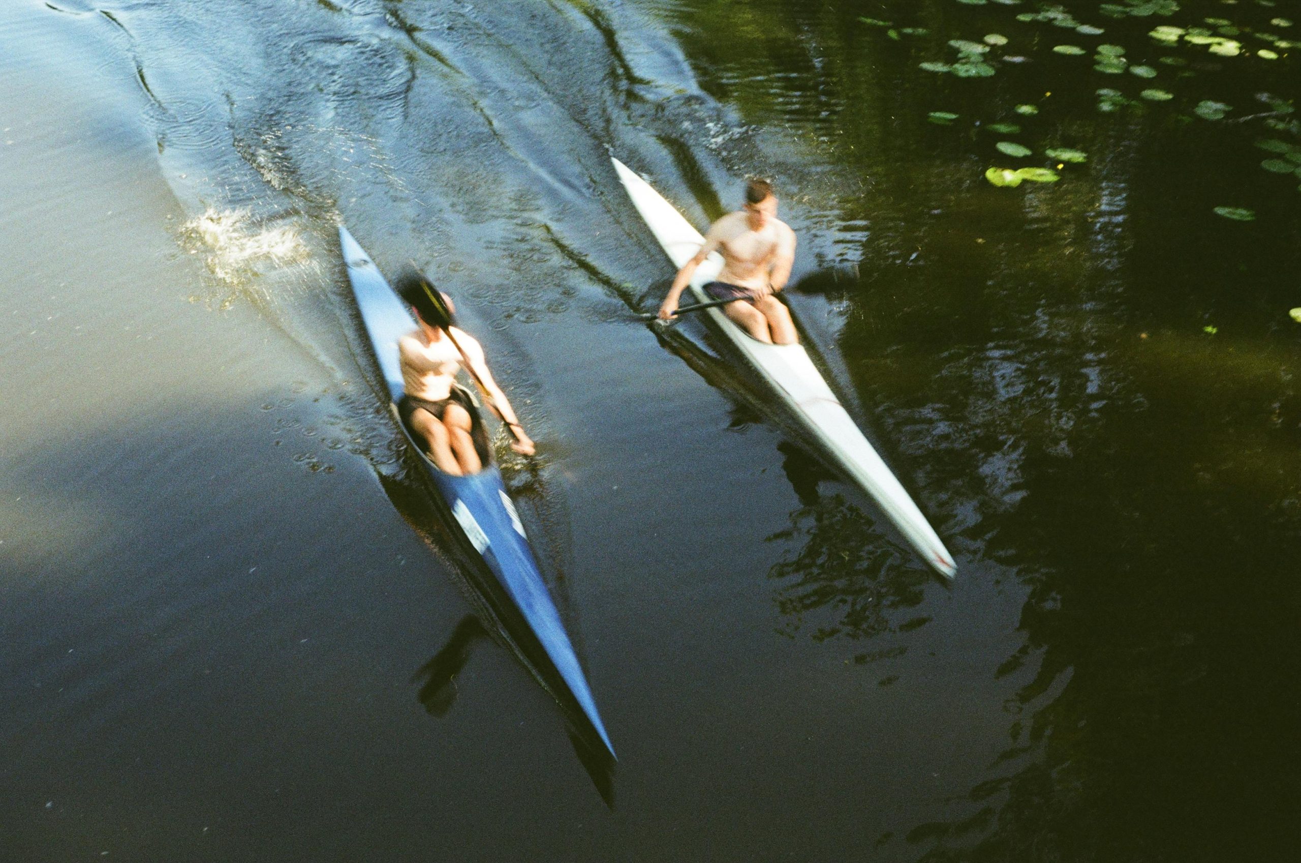 Two adults kayaking on a peaceful river in Kyiv, Ukraine, captured from above.