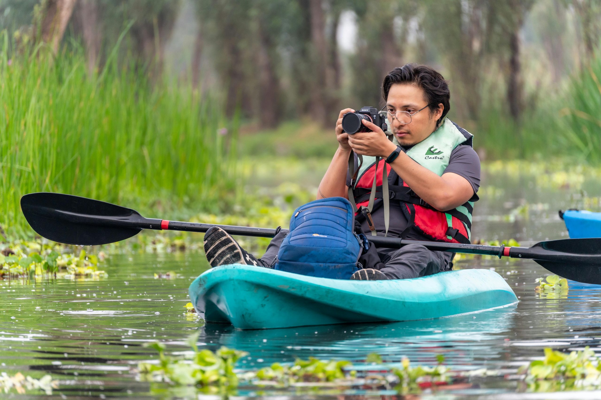 A man capturing photos while kayaking through serene canals in CDMX, Mexico.