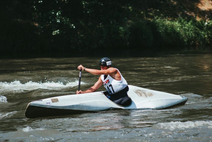 A sportsman canoeing on a river during a competition, showcasing strength and agility.
