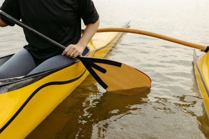 A woman paddles an outrigger in peaceful waters, showcasing recreational paddling and water sport activity.
