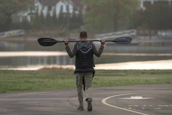 A kayaker carries paddles at Cove Island Park, Stamford, Connecticut during a serene early morning.