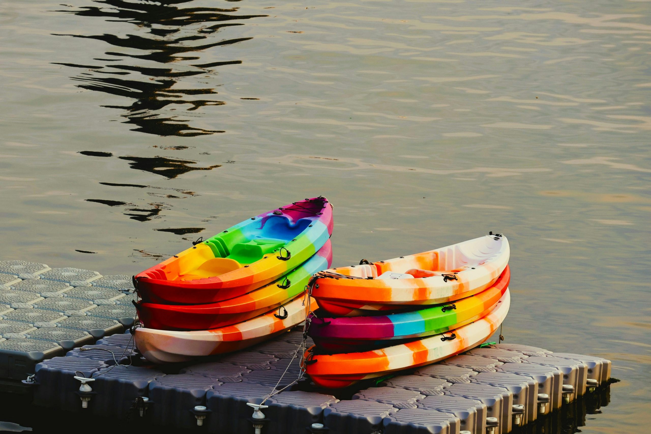 Vibrant kayaks stacked on a dock by the water during sunset in Taipei, Taiwan.