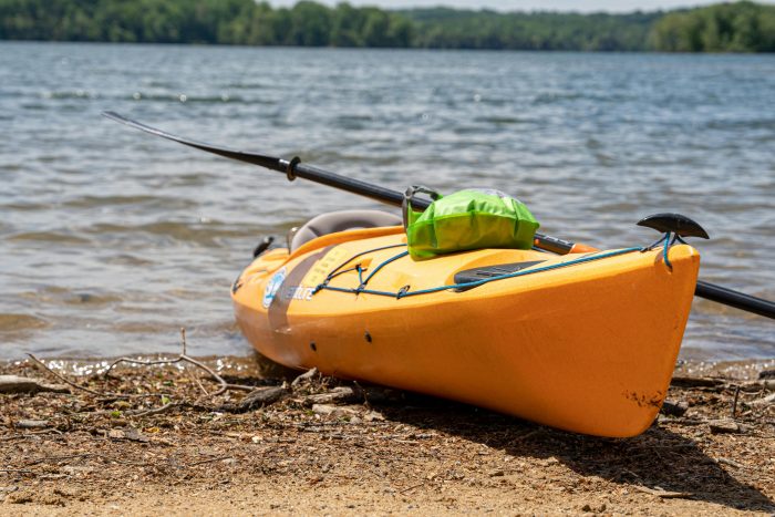 Vibrant yellow kayak resting on a tranquil lakeshore, ideal for summer adventures.