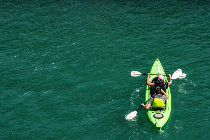 High angle shot of two people kayaking in clear turquoise water, embracing nature.