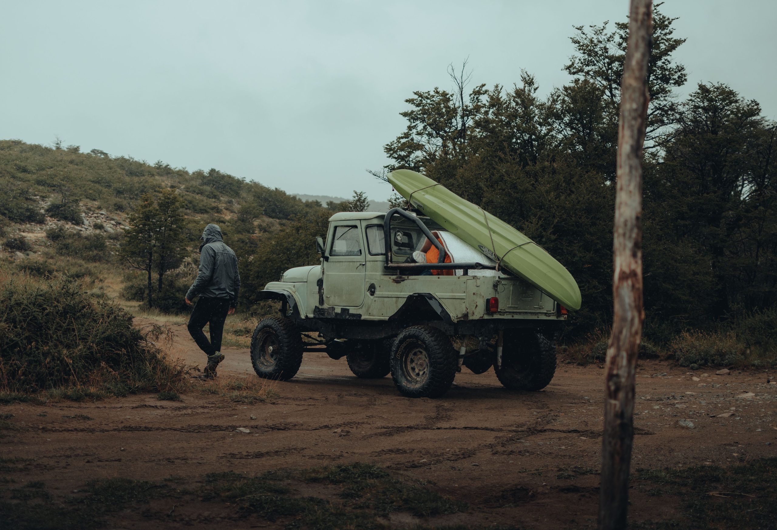 A rugged vehicle with a kayak in the wilderness, perfect for outdoor adventures.