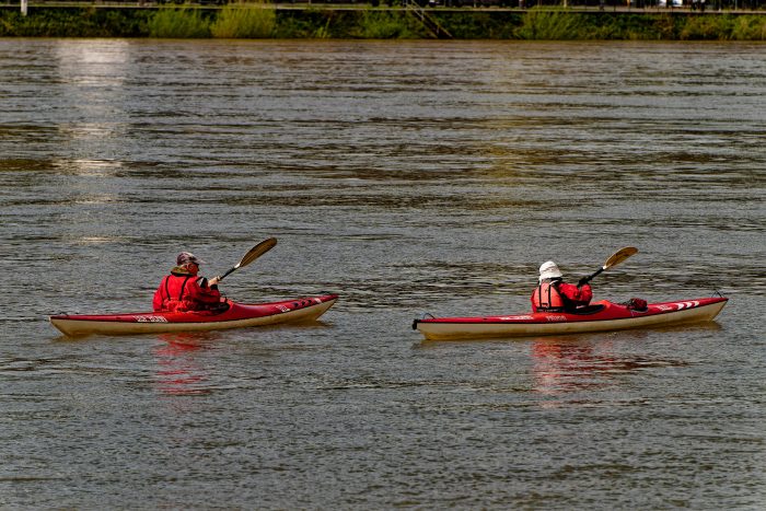 Two adults kayaking on a calm lake, enjoying leisure time and sport activities.