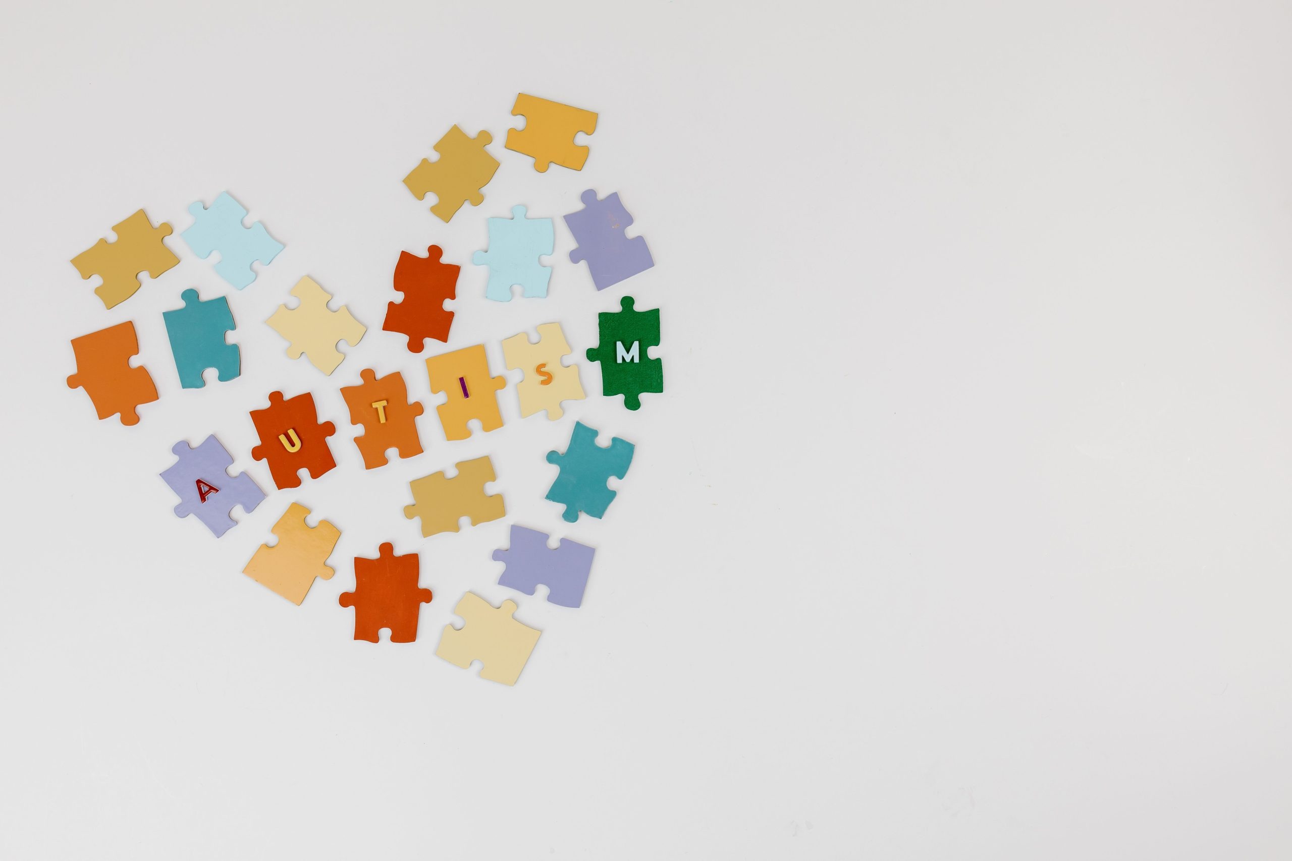Colorful puzzle pieces arranged in a heart shape emphasizing Autism awareness on a white background.